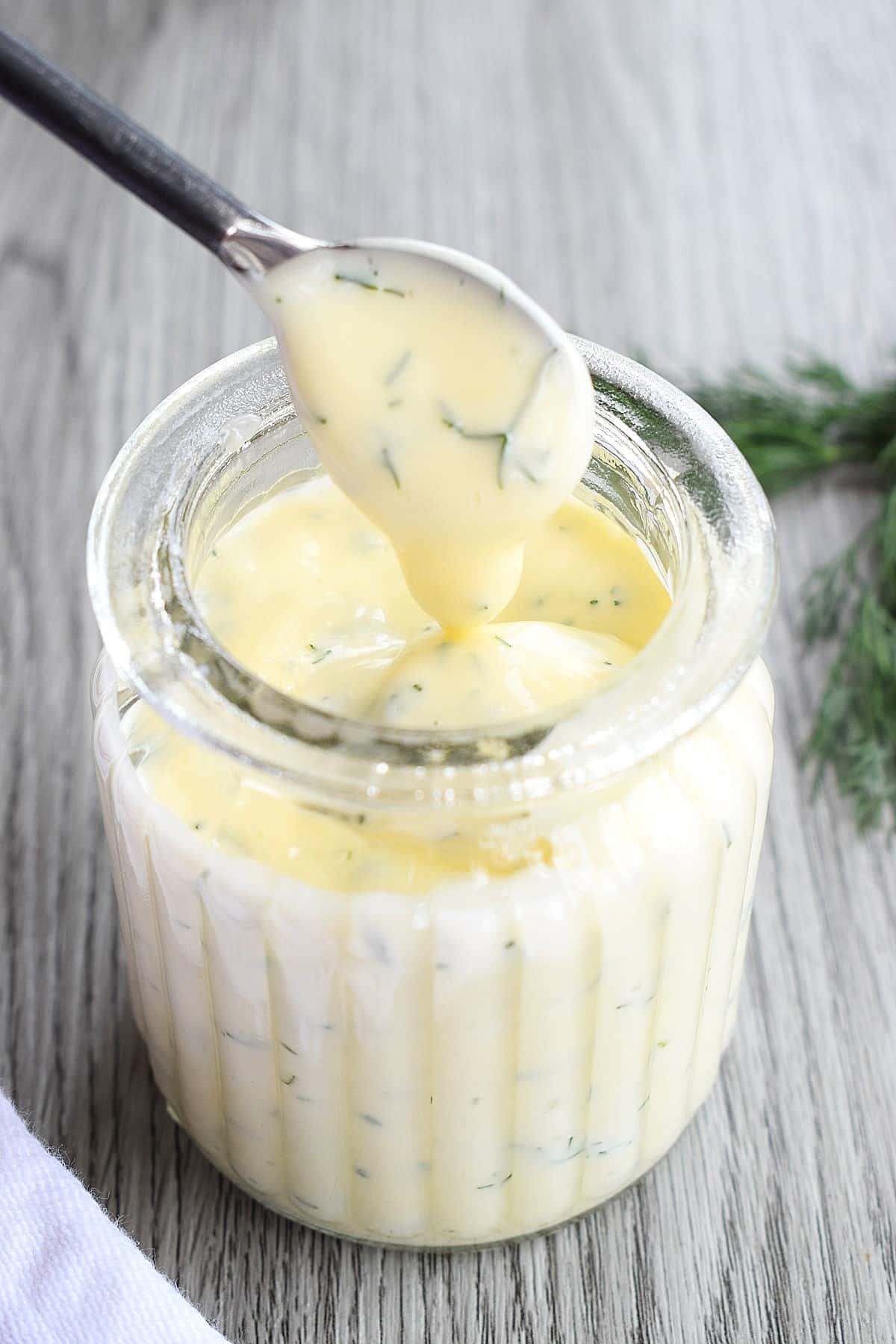 Honey dill sauce in small jar with mini serving spoon.