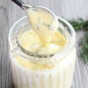 Honey dill sauce in small jar with mini serving spoon.