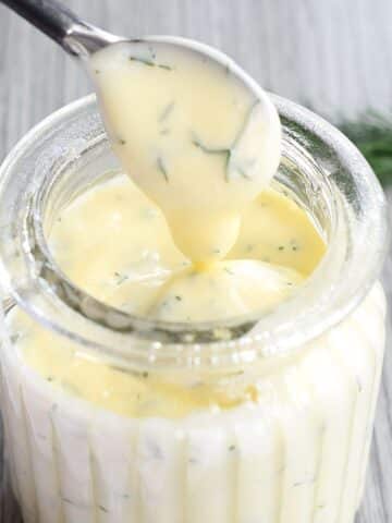 Honey dill sauce in small jar with mini serving spoon.