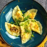 Pierogies with cheese filling on blue plate.