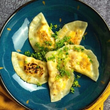 Pierogies with cheese filling on blue plate.