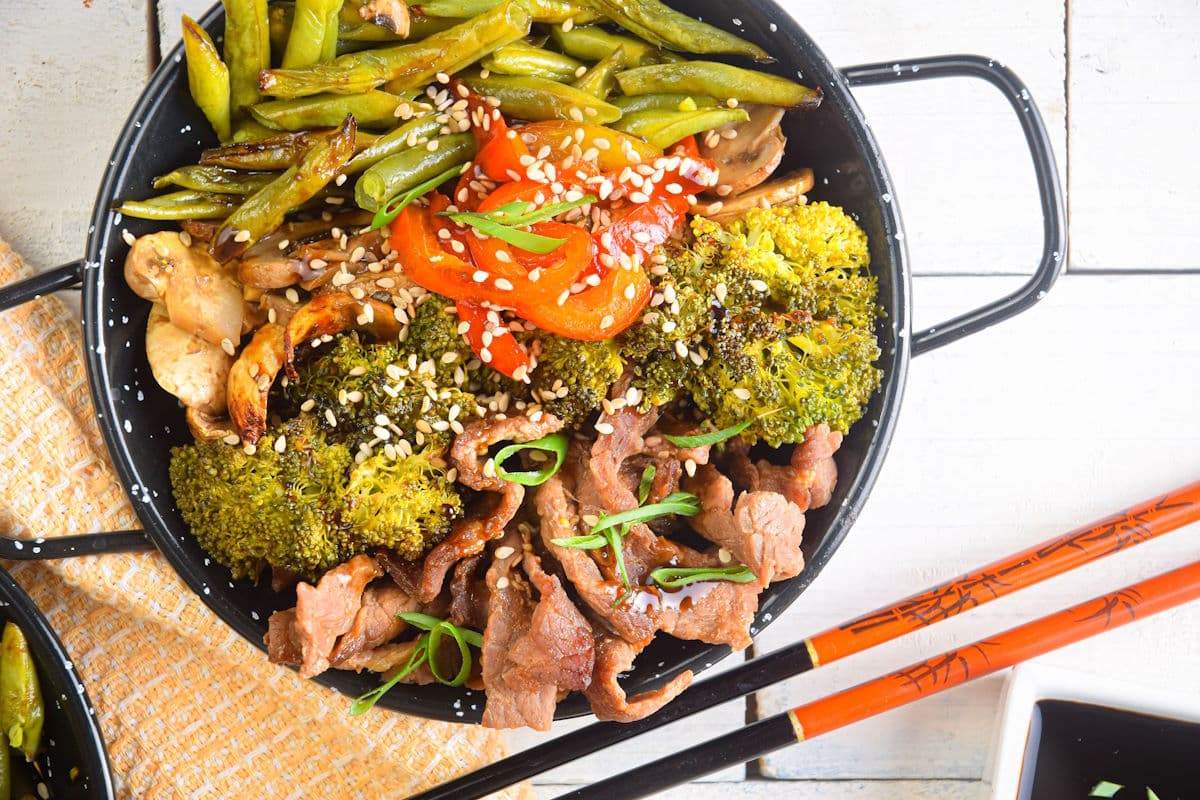 Beef teriyaki and broccoli in a bowl with chopsticks.