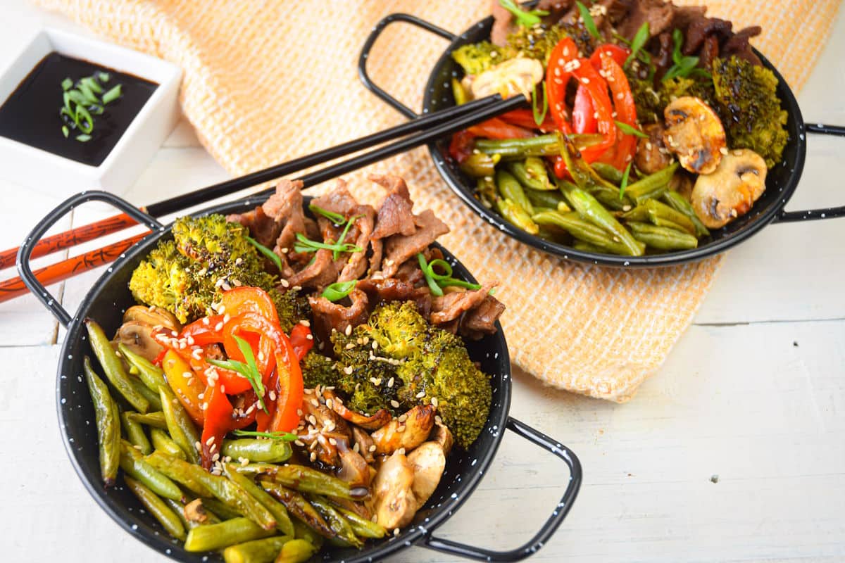 Beef and broccoli in bowls with chopsticks.