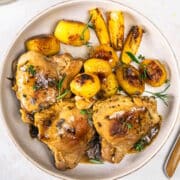 Greek lemon chicken thighs and baby potatoes on plate.