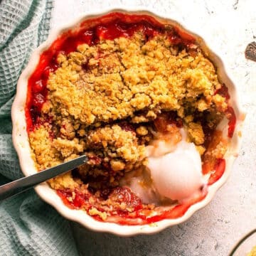 Strawberry crumble in tart dish with vanilla ice cream and spoon.
