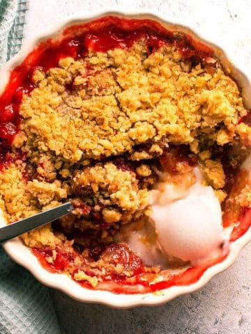 Strawberry crumble in tart dish with vanilla ice cream and spoon.