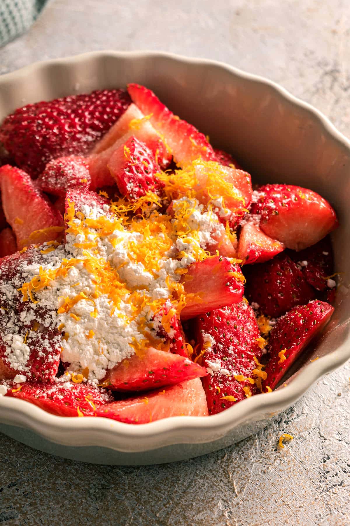 Strawberries, cornstarch and orange zest in tart dish.