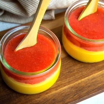 Strawberry pureé over custard in small jars.
