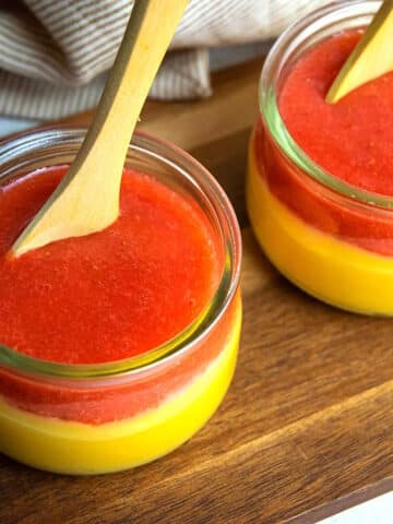 Strawberry pureé over custard in small jars.
