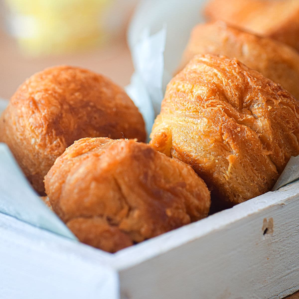 Golden biscuits in white wooden serving tray.