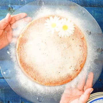 Yogurt cake on clear plate held by hands.