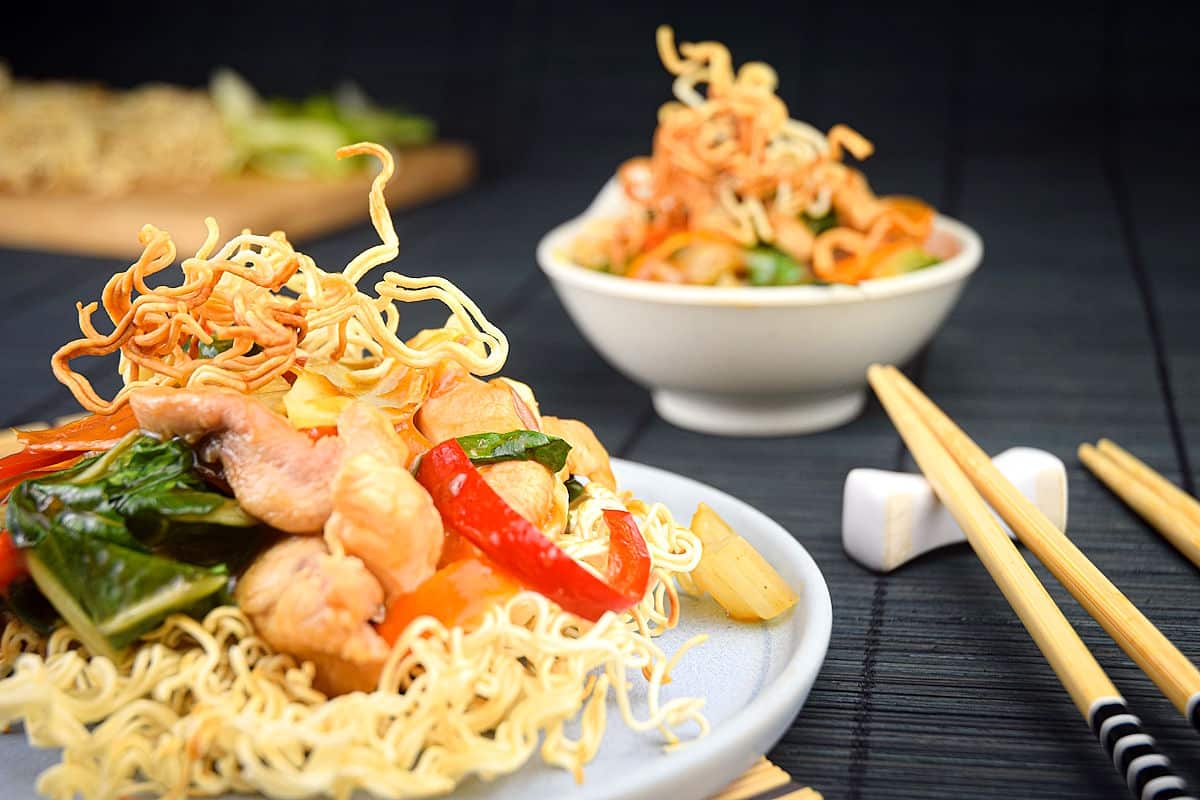 Crunchy chow mein noodle dish on white plate with chopsticks on the side.