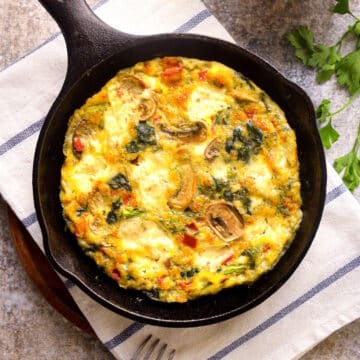 Electric skillet frittata in pan on kitchen towel.