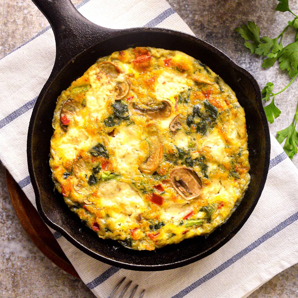 Electric skillet frittata in pan on kitchen towel.