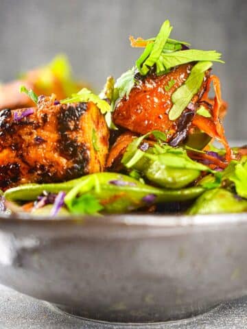 Glazed tofu with fresh herbs in bowl.