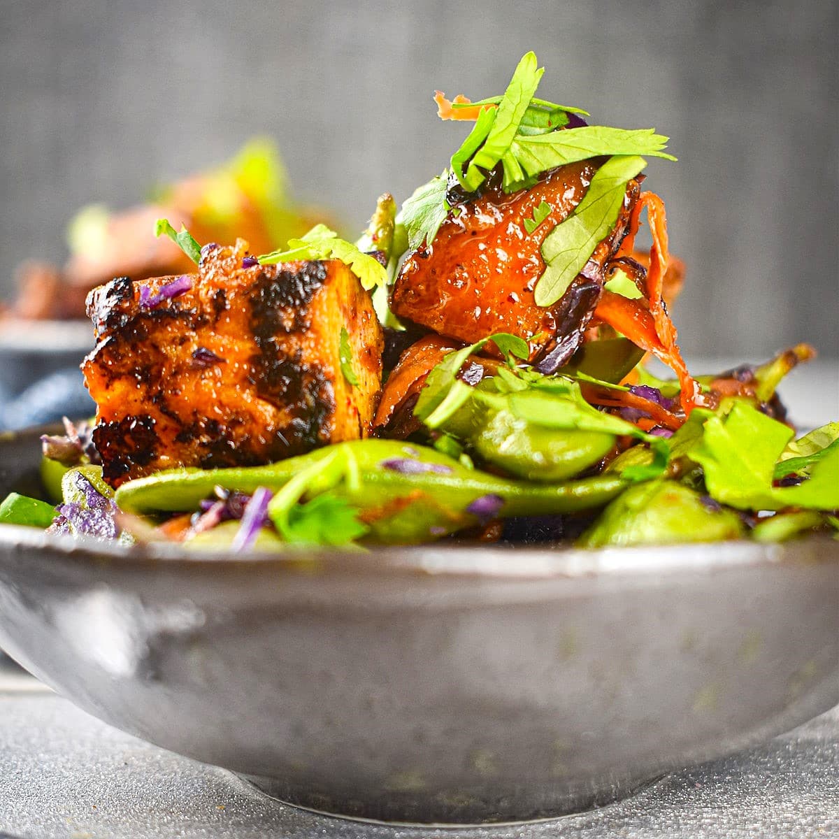 Glazed tofu with fresh herbs in bowl.