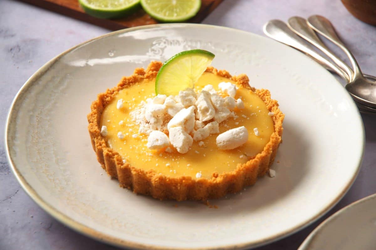 Key lime pie on plate with spoons on the side.