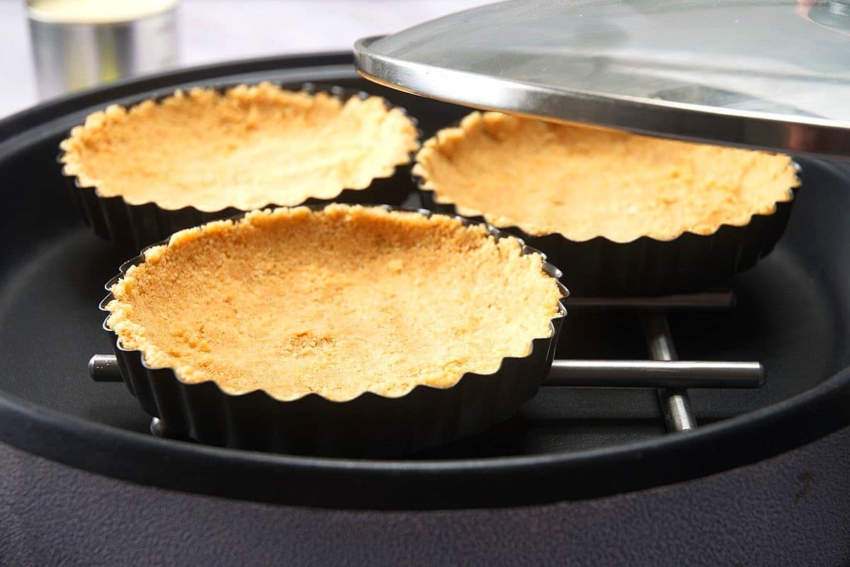 Mini tart shells with graham cracker crust in electric skillet.
