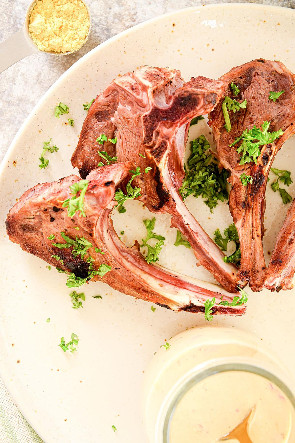 Lamb chops arranged on plate with chopped, fresh parsley.