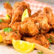 Lemon pepper chicken wings with lemon wedges.