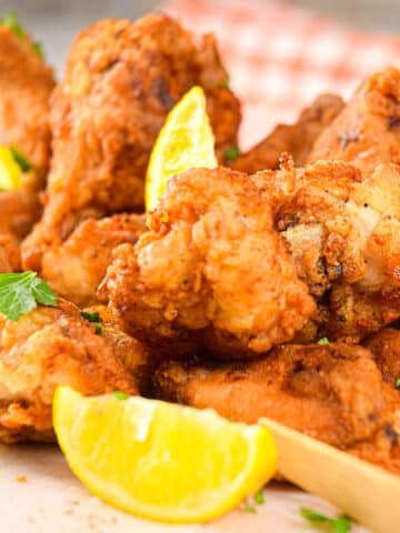 Lemon pepper chicken wings with lemon wedges.