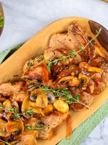 Pork chops with gravy, mushrooms and fresh thyme sprigs.