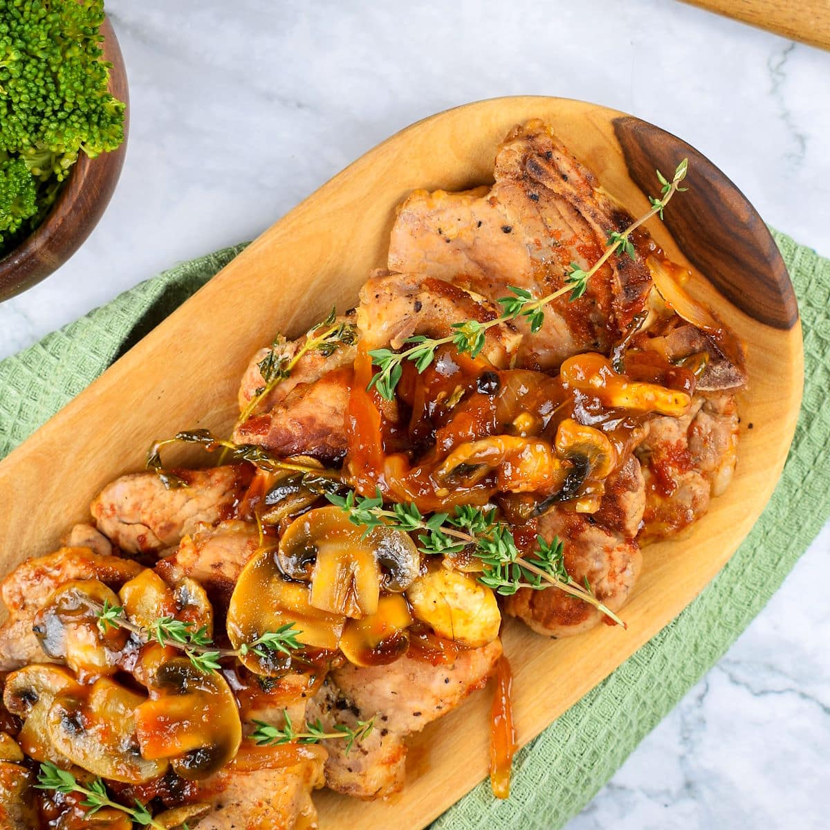 Pork chops with gravy, mushrooms and fresh thyme sprigs.