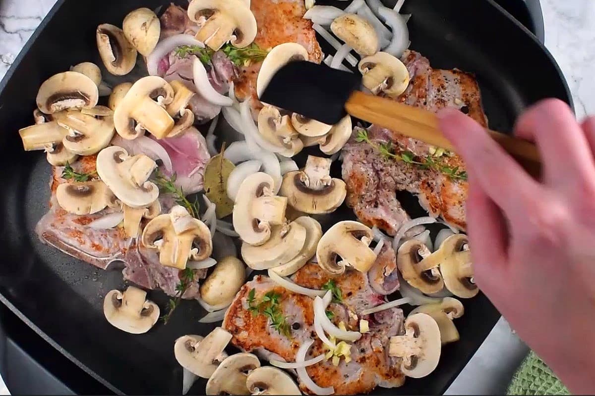 Mushrooms, onions and pork chops in electric skillet.