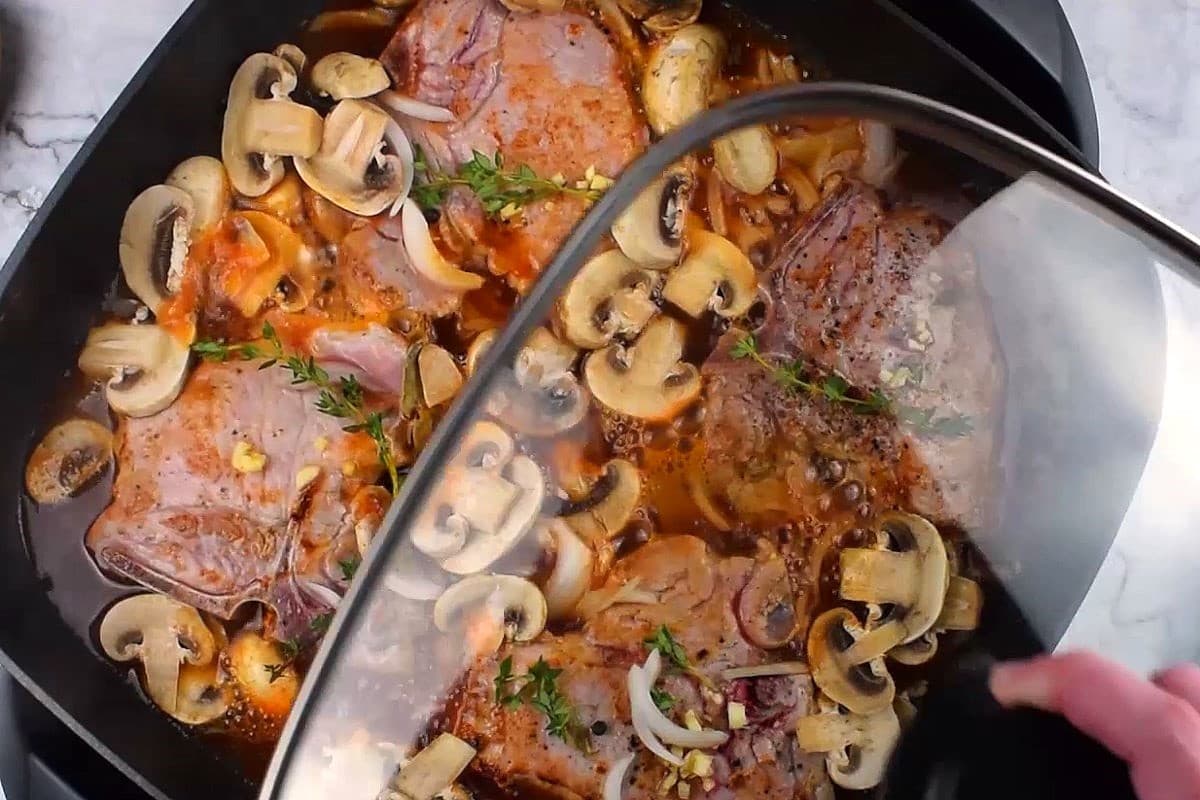 Pork chops in electric skillet with the lid.