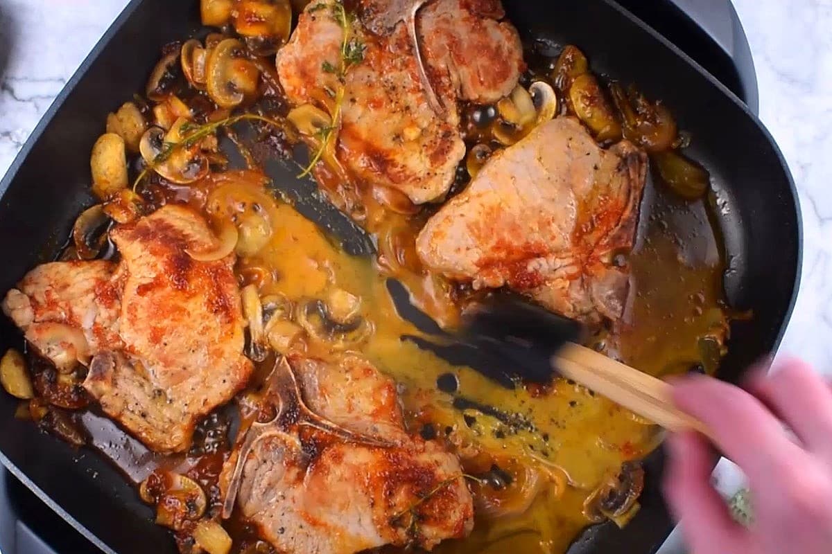 Cooked pork chops with beer gravy in electric skillet.