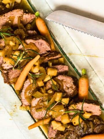 Electric skillet pot roast with vegetables on serving tray.