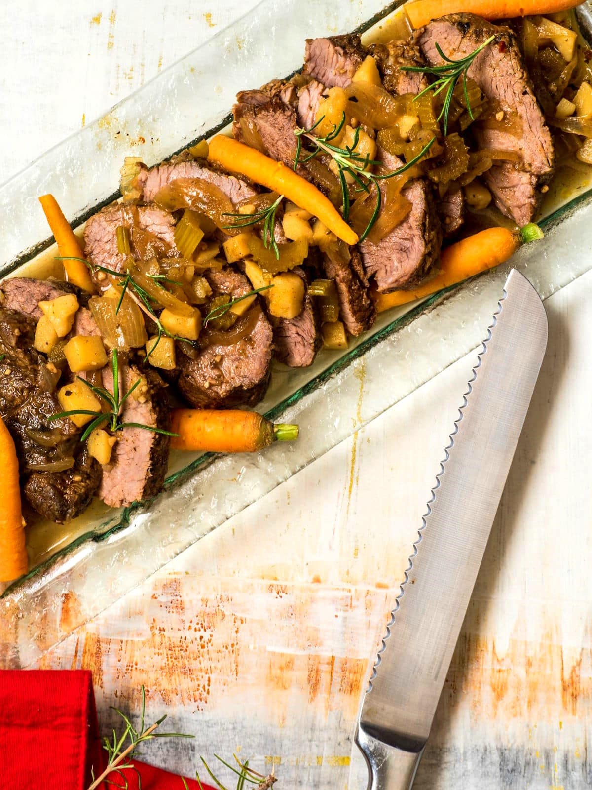 Electric skillet pot roast with vegetables on serving tray and knife on the side.