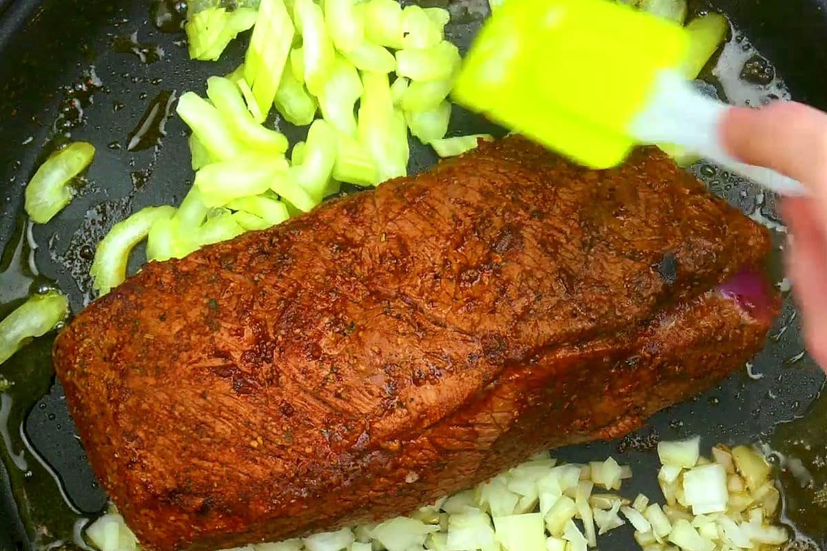 Seared pot roast in electric skillet with celery and onion.