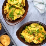 Cheesy scalloped potatoes in brown bowls on marble background.