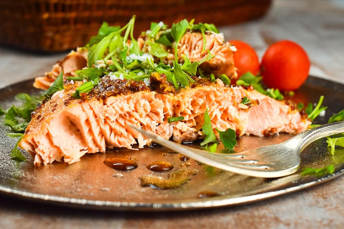 Electric skillet salmon with tomatoes and fork on plate.