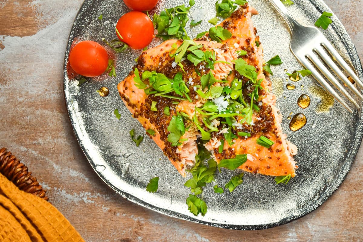 Electric skillet salmon with tomatoes and fork on fancy dish.