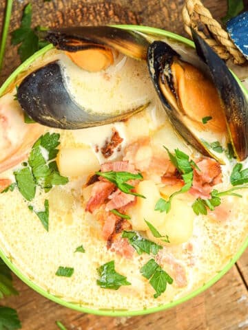 Seafood chowder in a bowl with wooden fish on the side.