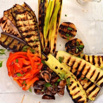 Grilled vegetables (escalivada) on clear, glass plate.