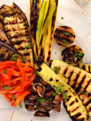 Grilled vegetables (escalivada) on clear, glass plate.