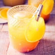 Fall pumpkin party punch in a glass with orange slice garnish.