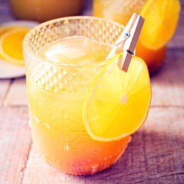 Fall pumpkin party punch in a glass with orange slice garnish.
