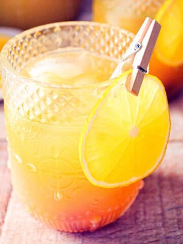 Fall pumpkin party punch in a glass with orange slice garnish.