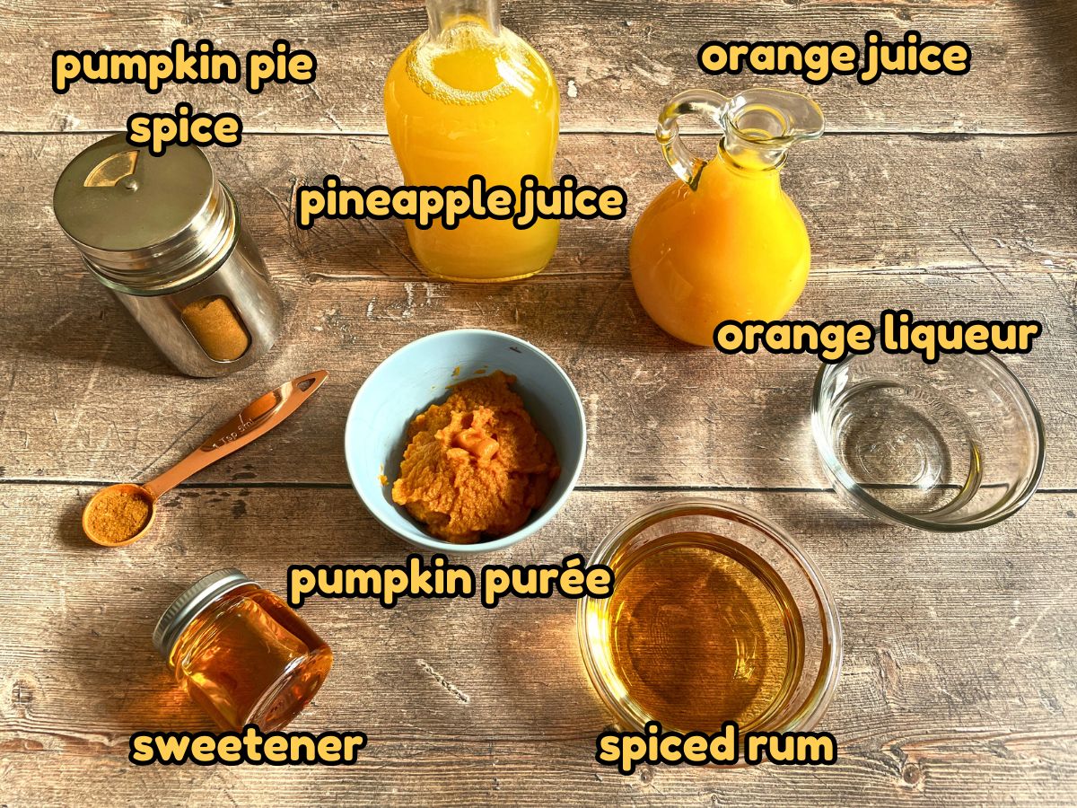 Fall pumpkin party punch ingredients labeled on wooden background.