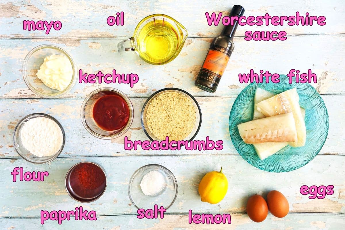 Fish sticks with dipping sauce ingredients labeled on light blue, wooden background.