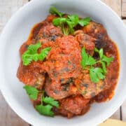Turkey meatballs in tomato sauce in bowl with fresh parsley.