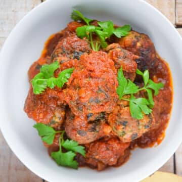 Turkey meatballs in tomato sauce in bowl with fresh parsley.