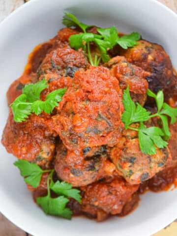 Turkey meatballs in tomato sauce in bowl with fresh parsley.