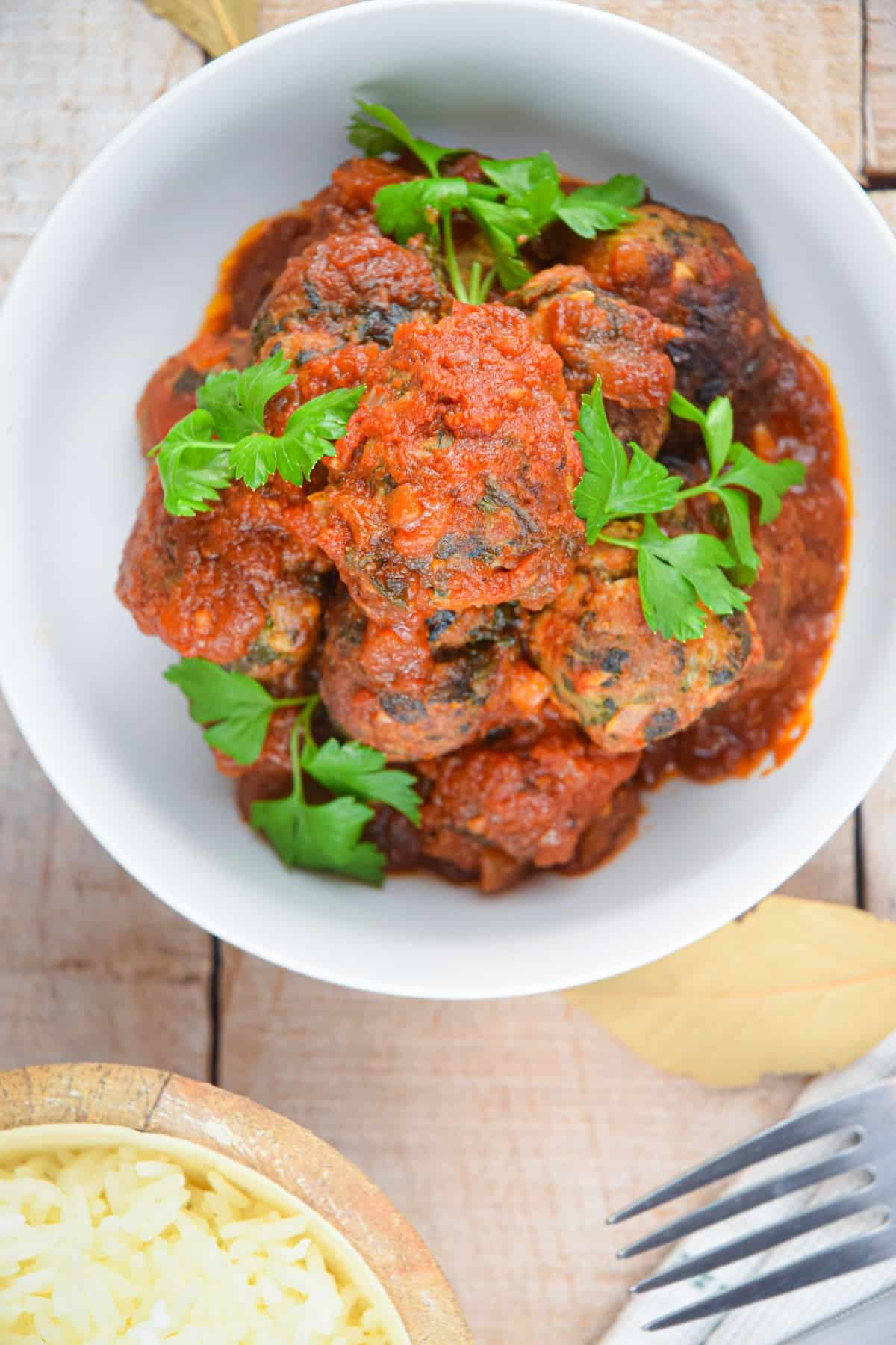Turkey meatballs in tomato sauce in bowl with fresh parsley.