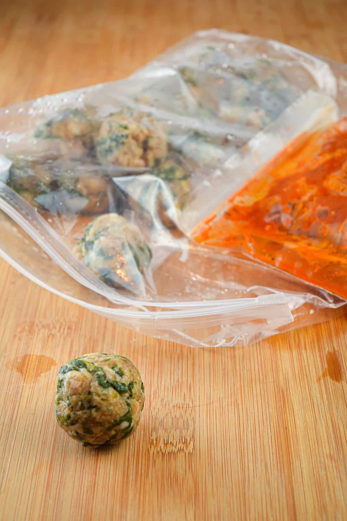 Raw turkey meatballs and tomato sauce in zip-top bags.