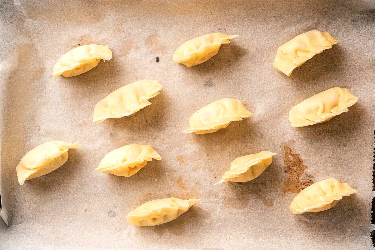 Frozen kimchi dumplings on sheet pan.